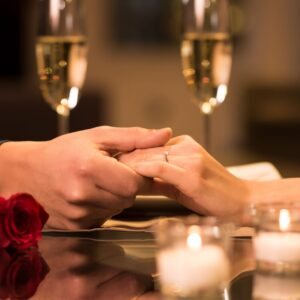 Closeup,Of,Couple,Hands,On,Restaurant,Table,With,Two,Glasses